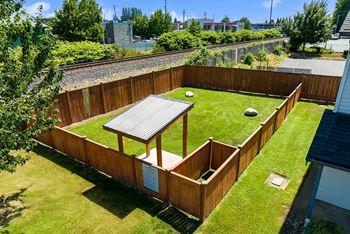 Fully fenced dog park with bright green grass and an undercover area. Pet friendly Apartments. at Quilceda Gardens, Marysville, WA, 98270